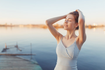 Summer Sunny walk along the beach. Emotional beautiful girl at sunset on the pier.