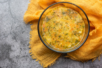 Soup kulesh with millet, potatoes and carrots in a clear bowl on an orange cloth. Kulesh dense Ukrainian traditional soup. 