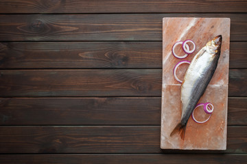 Fish herring with onions on a salt Himalayan block. Top view. Method of salting fish