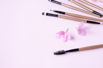 Flower and set of cosmetic brushes on a pink background