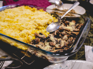 Glass dish with cooked corn with vegan grated cheese and sautéed mushrooms with vegan cheese