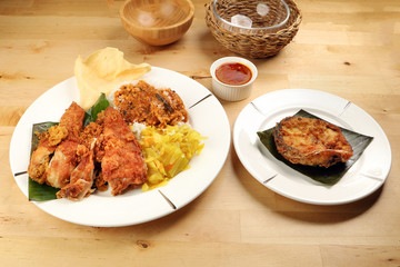 Traditional Malaysian Indian food white rice cabbage vegetable meat deep fried chopped chicken leg topped up with spicy mix gravy wood table background