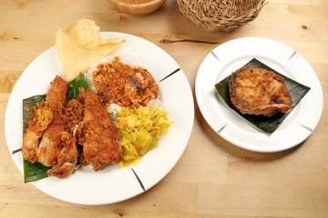 Traditional Malaysian Indian food white rice cabbage vegetable meat deep fried chopped chicken leg topped up with spicy mix gravy wood table background