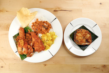 Traditional Malaysian Indian food white rice cabbage vegetable meat deep fried chopped chicken leg topped up with spicy mix gravy wood table background