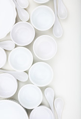 Dishware concept. White empty porcelain bowls and teaspoons on white background.
