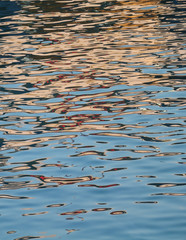 Reflections make the sea sparkle. Orange and red colors on transparent water surface background.