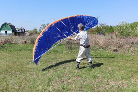 Man learns to manage homemade kitewing on the lawn in summer