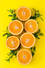 Fresh orange citrus fruit with leaves on yellow paper background. Juicy and sweet fruit. Concentration of vitamin C. Flat lay.