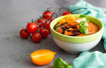 Tomato gazpacho soup garnish with cucumber, tomato, basil and balsamic sauce. Spanish cuisine. Grey stone background.