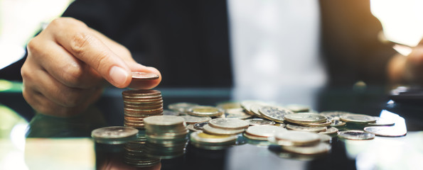 Businesswoman stacking coins on the table for saving money and financial concept