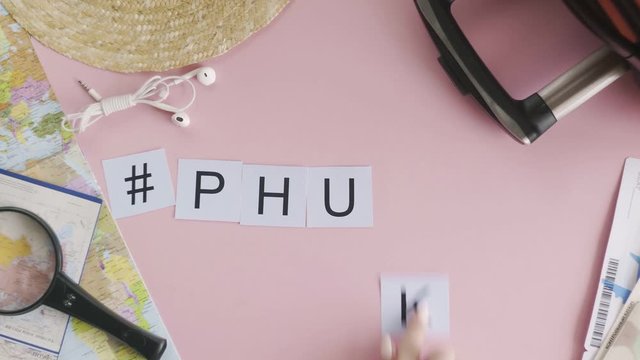Top view hands laying on pink desk word PHUKET