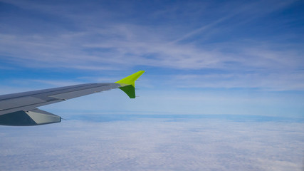 Fototapeta premium Airplane. A beautiful wing of an airplane flying high in the sky, above clouds, small towns, forests and fields. Closeup. Travel, tourism and vacation concept.For design. 