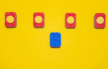 Colored dishwasher tablets on a yellow background. Minimalist design composition
