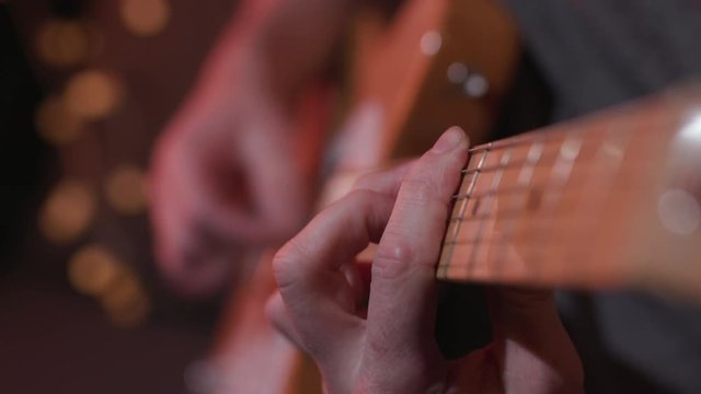 Male guitar player strums chords in music studio on electric guitar, closeup