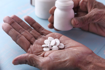 Elderly woman pouring pills from bottle on hand with copy space 