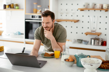 Fototapeta na wymiar Handsome man preparing breakfast at home. Young man drinking coffee in kitchen.