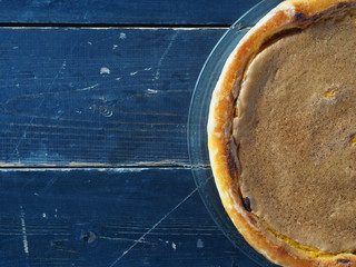Orange pumpkin round pie.Natural vegetarian dessert on a dark wooden background. Top view, flat styling.