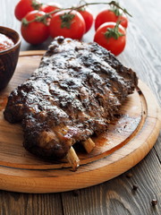 Summer barbecue - grilled ribs with fresh tomatoes and sauce on a wooden board