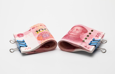 Two stacks of rolled up Chinese one hundred Renminbi yuan banknotes clamped with paper clips on white background.