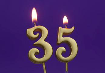 Burning golden birthday candles on blue background, number 35