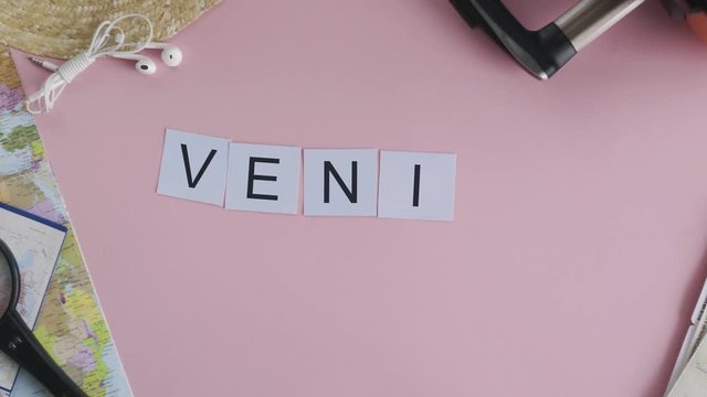 Top view hands laying on pink desk word VENICE