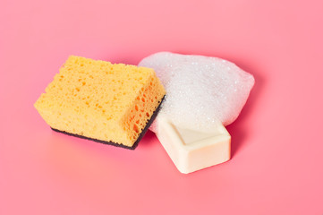 Brick of soap with foam bubbles near sponge on pink background. Washing, cleaning concept