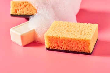 Brick of soap with foam bubbles near sponge on pink background. Washing, cleaning concept