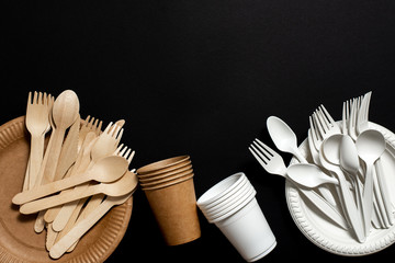 disposable forks, spoons, plates and glasses from environmentally friendly materials on a black...