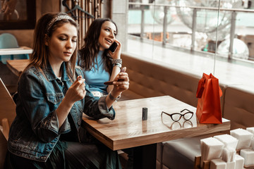 Cafes and bars. Two girls are sitting at a cafe table. Discussion of shopping. Girlfriends in a cafe.