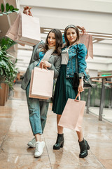 Trade, buyers. Two beautiful girls make purchases in a shopping center, go shopping. The joy of consumption.