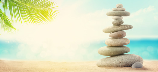 Pyramid of sea pebbles on a sunny sand beach