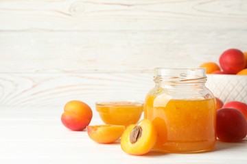 Composition with tasty apricots and jam on white wooden table