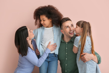 Happy couple with little adopted children on color background