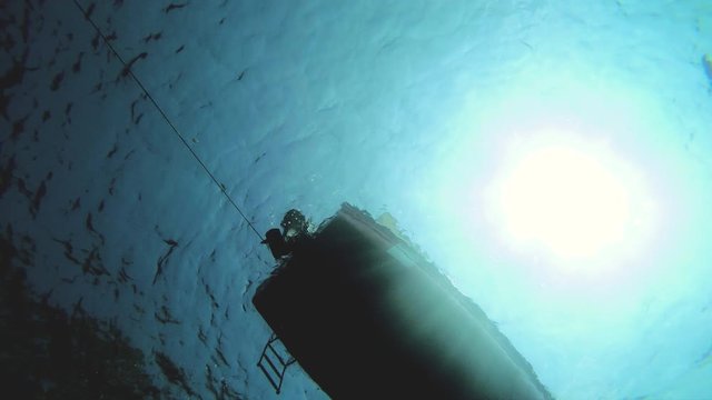 Underwater shot of bottom of boat floating with engine turned down.