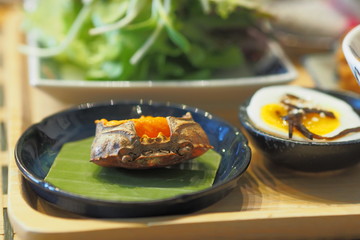 Crab eggs in Crab shell on banana leaf with half boiled egg on a table - Breakfast set Japanese style