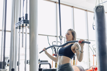Fototapeta premium attractive athletic girl trains shoulders in simulator. view of the back muscles. healthy lifestyle.