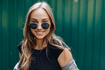 young pretty attractive girl in denim clothes in glasses on a simple dark green background with place for text.