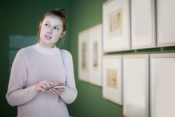 woman using smartphone and standing in art museum