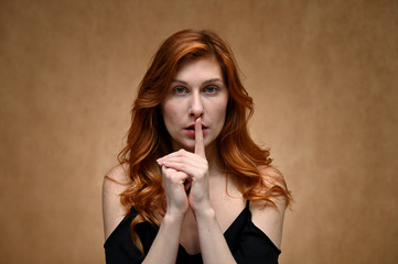 Studio large photo portrait of Caucasian young actress woman with long red hair on a beige...