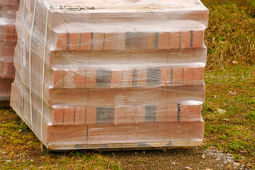 Finishing bricks are transported on a wooden pallet in plastic packaging