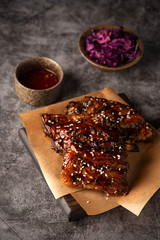 barbecue pork ribs on a wooden board, gray background, copy space
