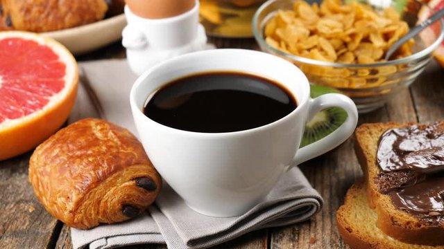 coffee pouring in cup with croissant, fruit, cereal and egg- slow motion