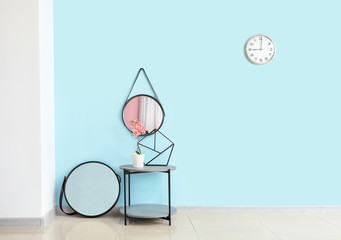 Table with houseplant and mirrors near color wall in living room