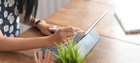 Cropped image of graphic designer writing/sketching on computer tablet with keyboard case by using...