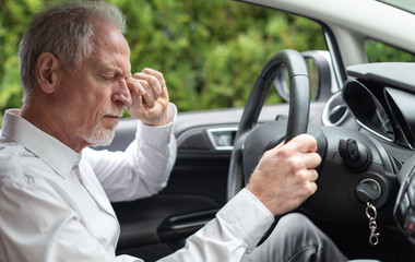 Tired man rubbing his eyes in car
