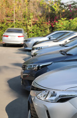 Closeup of front side of soft blue car and other cars parking in outdoor parking lot in sunny day.  Vertical view.
