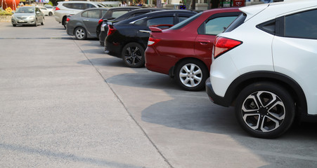 Closeup of rear, back side of white car with  other cars parking in outdoor parking area in sunny day.