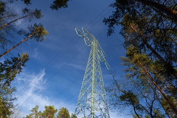 Słup energetyczny wysokiego napięcia na tle nieba pośród drzew © Grzej