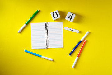Date on July 4 calendar, notepad, felt-tip pens, on yellow background