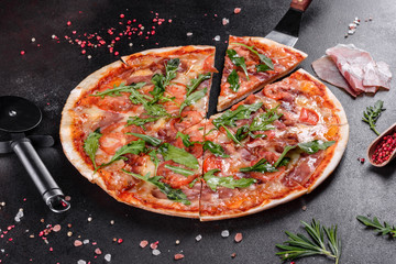 Fresh pizza baked in oven with arugula, salami, cherry tomatoes and mozzarella